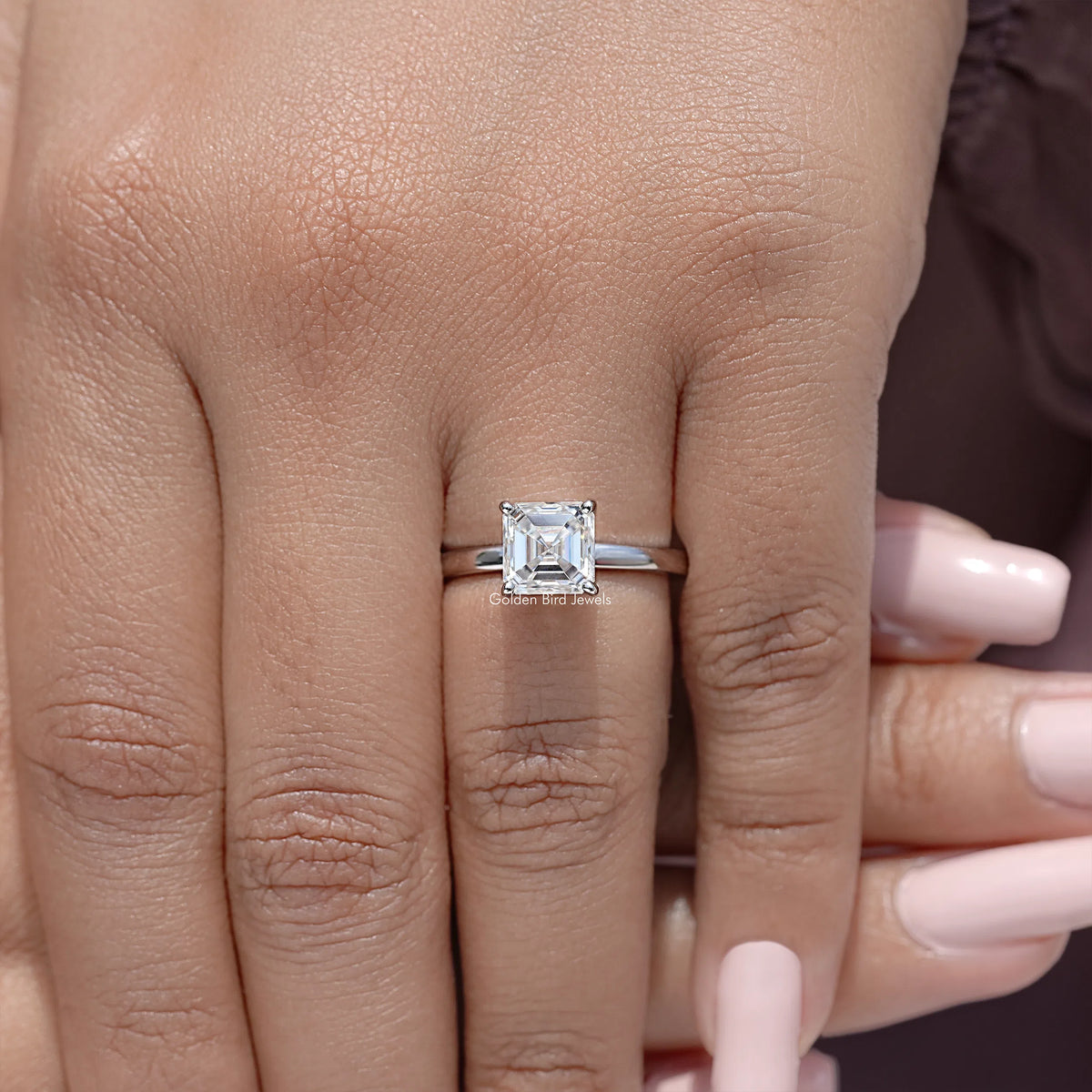 Sterling silver asscher-cut solitaire ring with square stone, slim band visible on hand