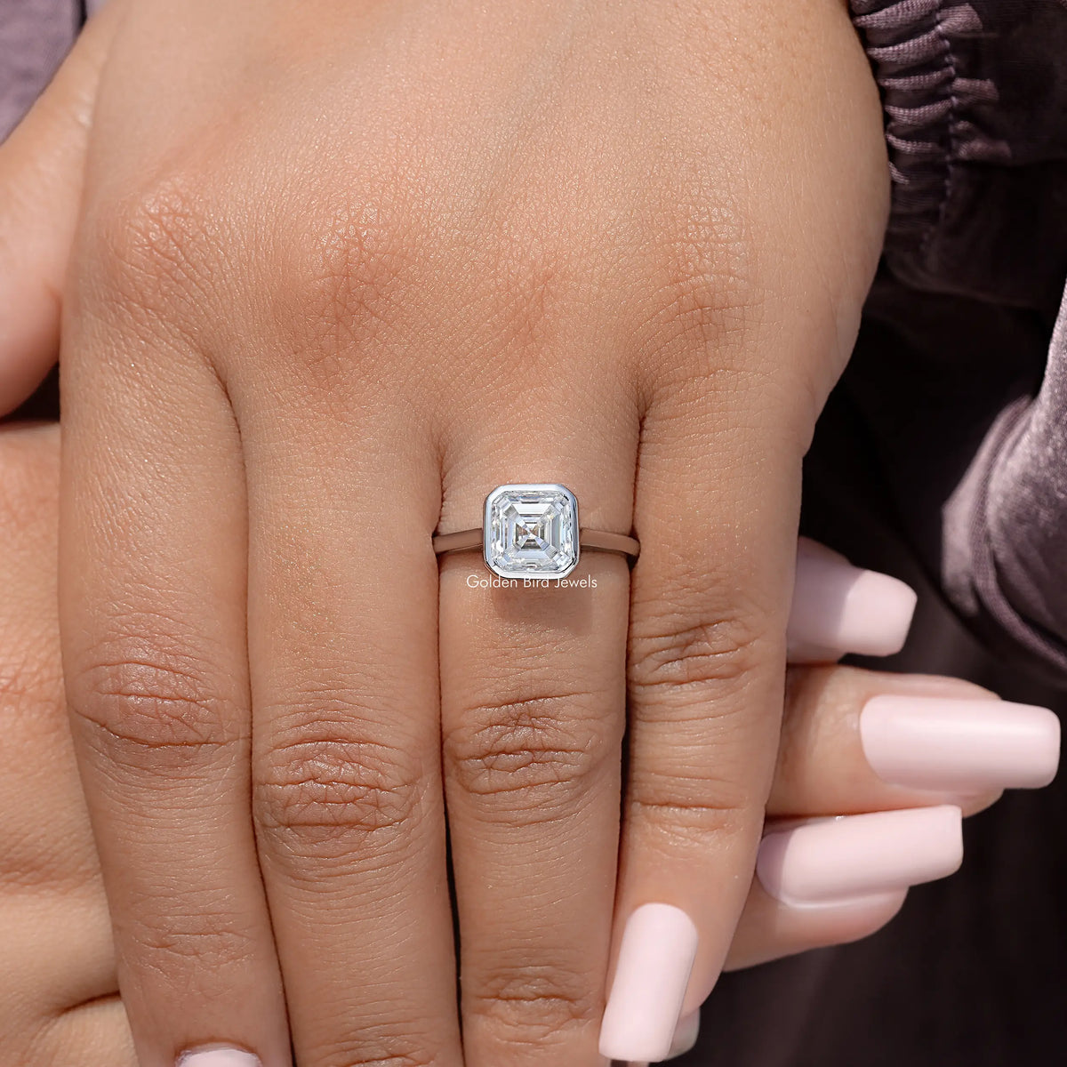 Sterling silver asscher-cut moissanite bezel-set engagement ring close-up on hand