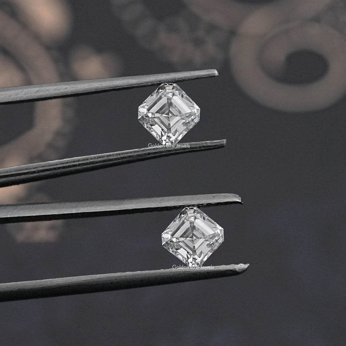 Asscher-cut lab-grown diamond pair held in tweezers, square step-cut stones