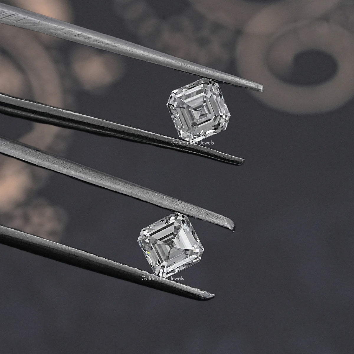 Asscher-cut lab-grown diamond pair close-up in tweezers, square step-cut stones