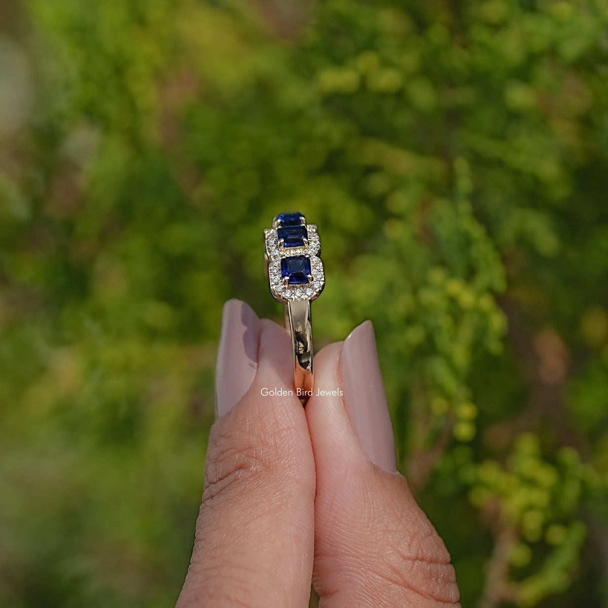 Blue gemstone halo band ring with square center stone and clear halo border