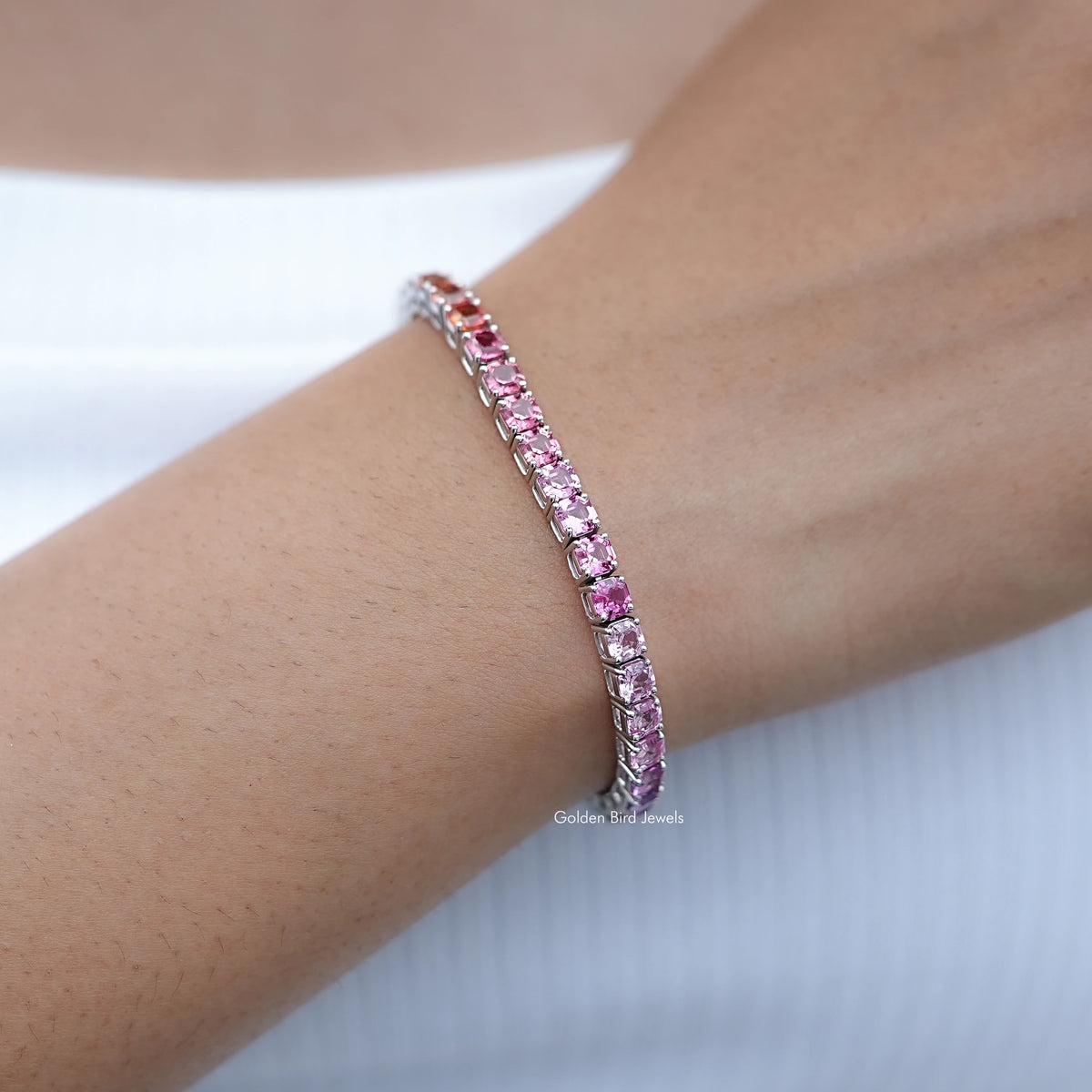 Gradient gemstone tennis bracelet close-up, lilac and pink stones with silver prongs.