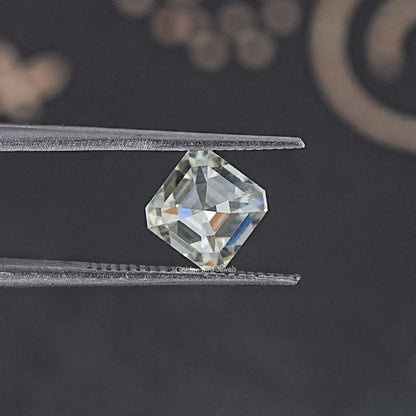 Asscher-cut moissanite loose stone held between tweezers, off-white, 2.85 CT