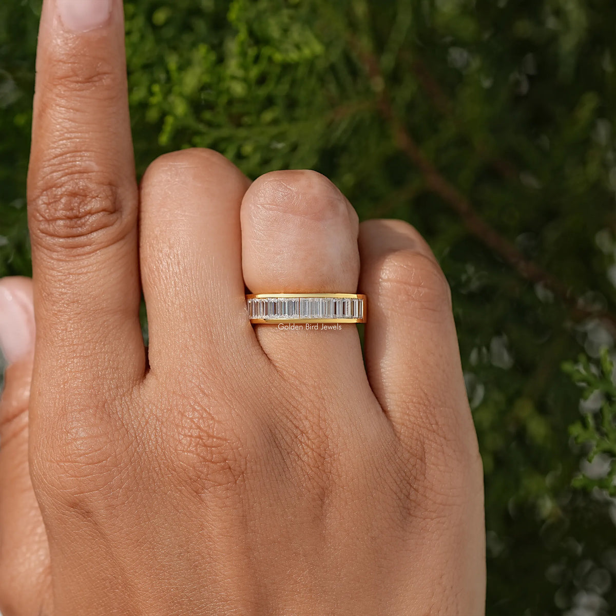 Yellow gold baguette channel-set moissanite wedding band on finger