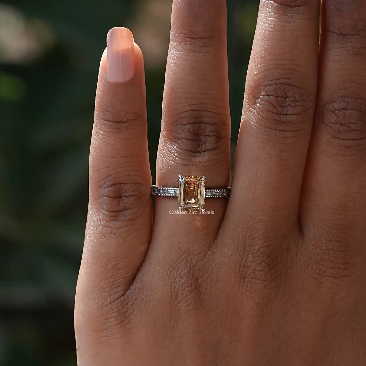 Sterling silver engagement ring on hand with square golden center stone and baguette accents