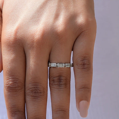 Silver eternity wedding band with baguette-cut stones, worn on finger
