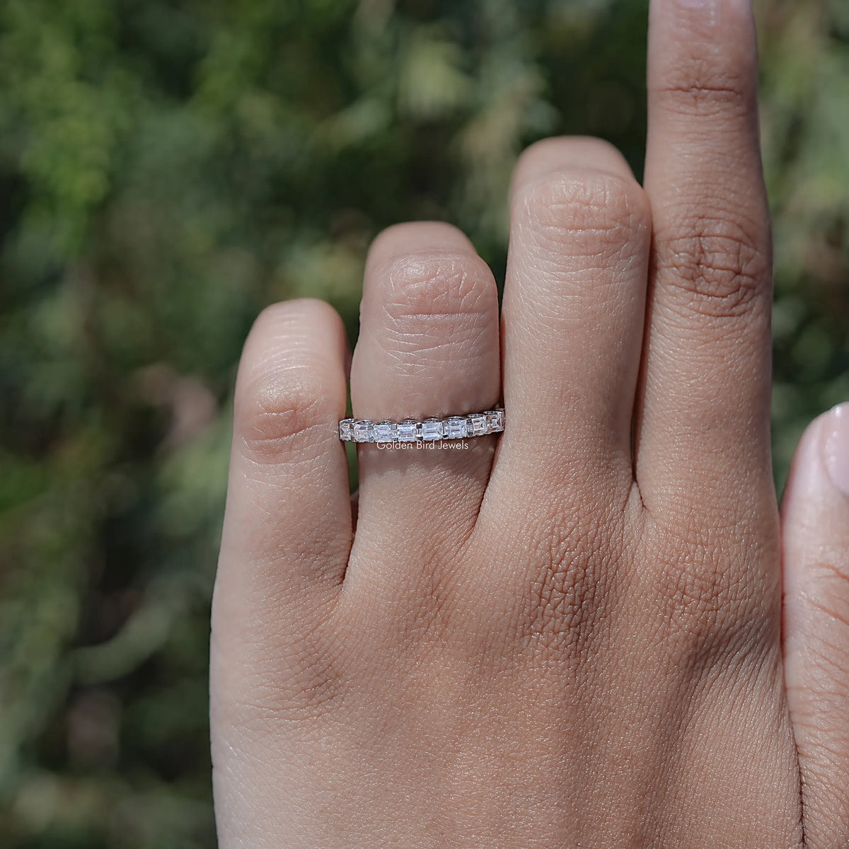 Silver-toned half eternity wedding band with baguette-cut moissanite, on finger