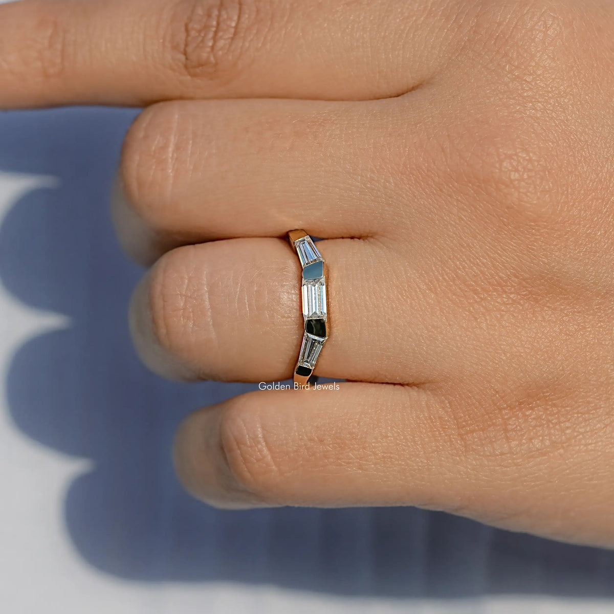 Three-stone baguette-cut ring close-up showing bezel settings and metal band