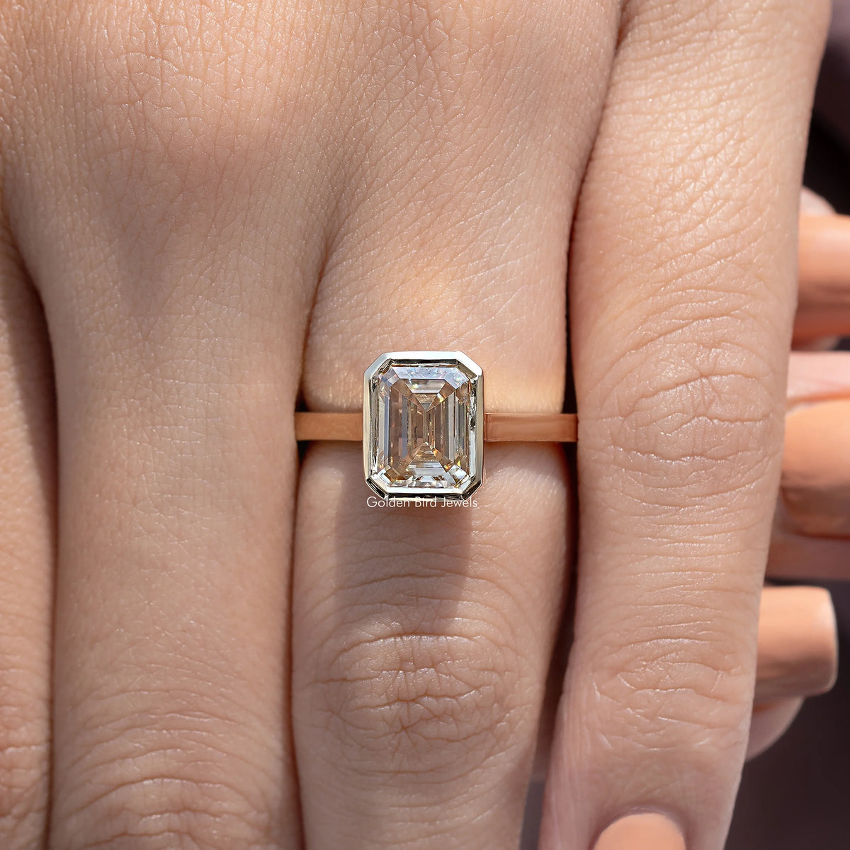 Close-up of rose-gold solitaire ring with emerald-cut center stone and band