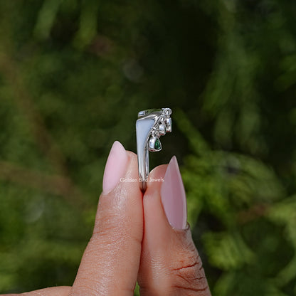 Curved profile engagement ring with green bezel-set gemstones, silver metal
