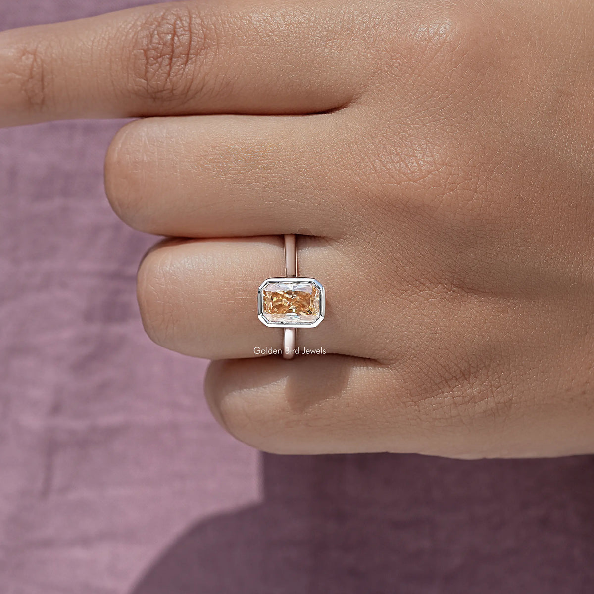 Radiant-cut solitaire ring with rose-gold bezel and square center stone