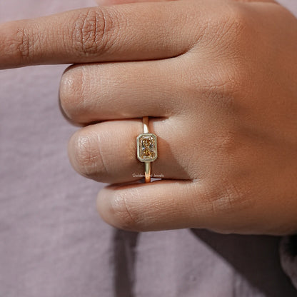 Gold-tone bezel-set radiant-cut moissanite solitaire ring on finger close-up