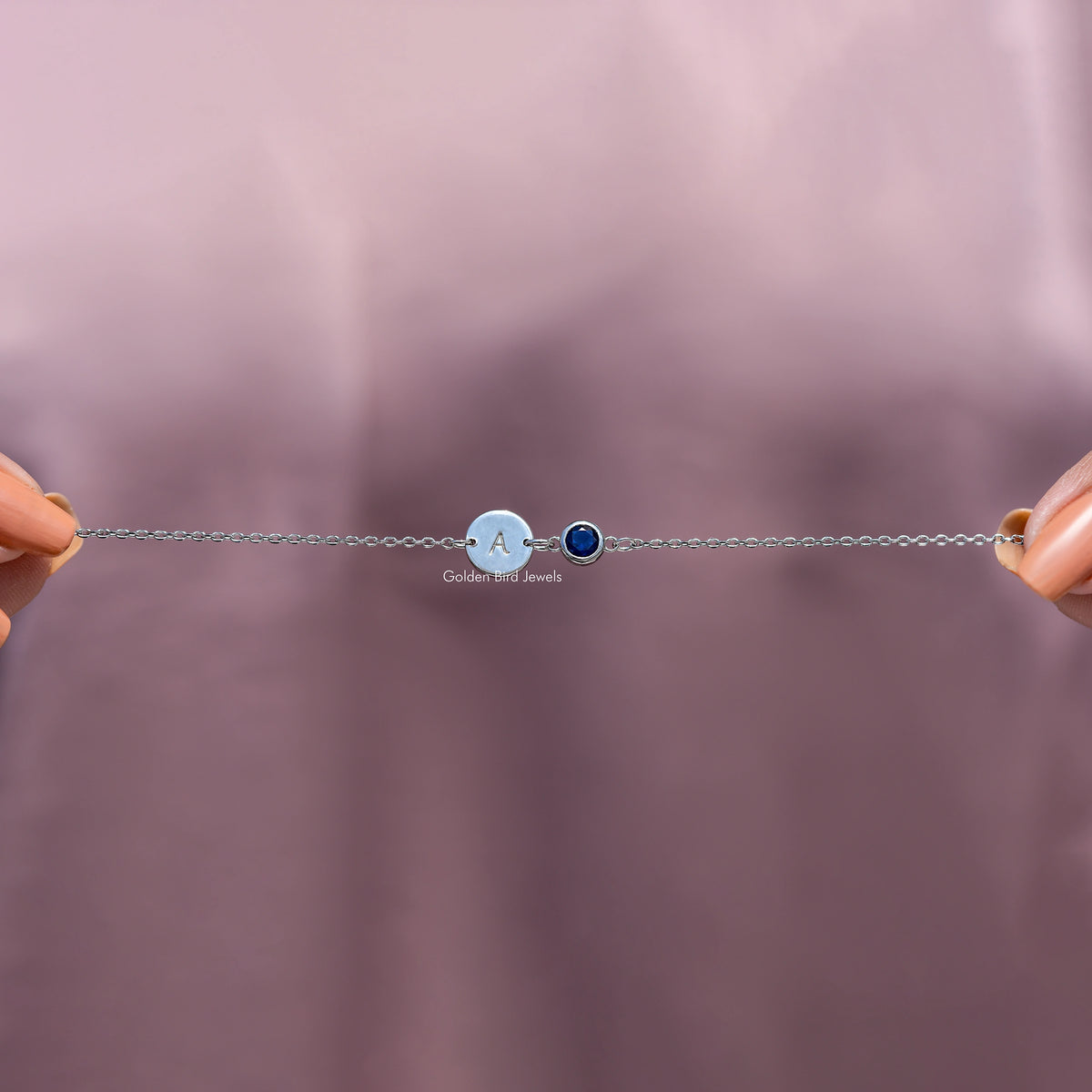 Minimal bracelet view: round light blue initial A charm with dark blue gemstone bezel