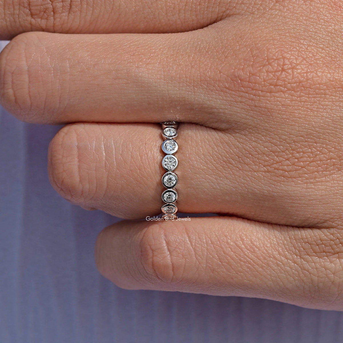 Silver-toned round bezel lab diamond band with stones in a vertical row, side view