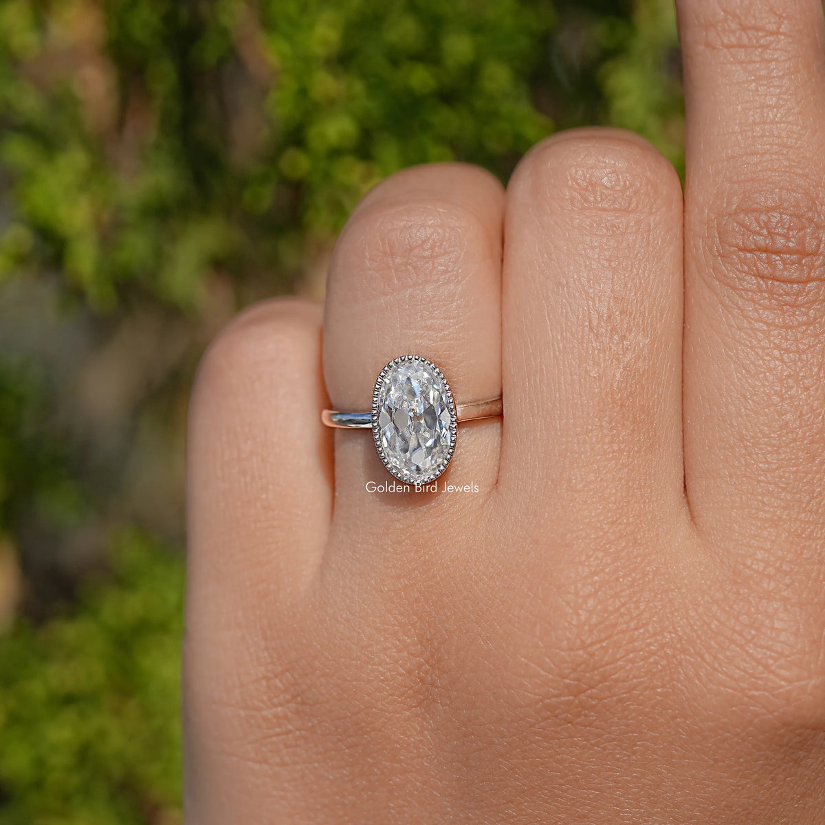 Oval bezel-set moissanite ring on hand, rounded bezel set stone