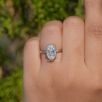 Oval bezel-set moissanite ring on hand, rounded bezel set stone