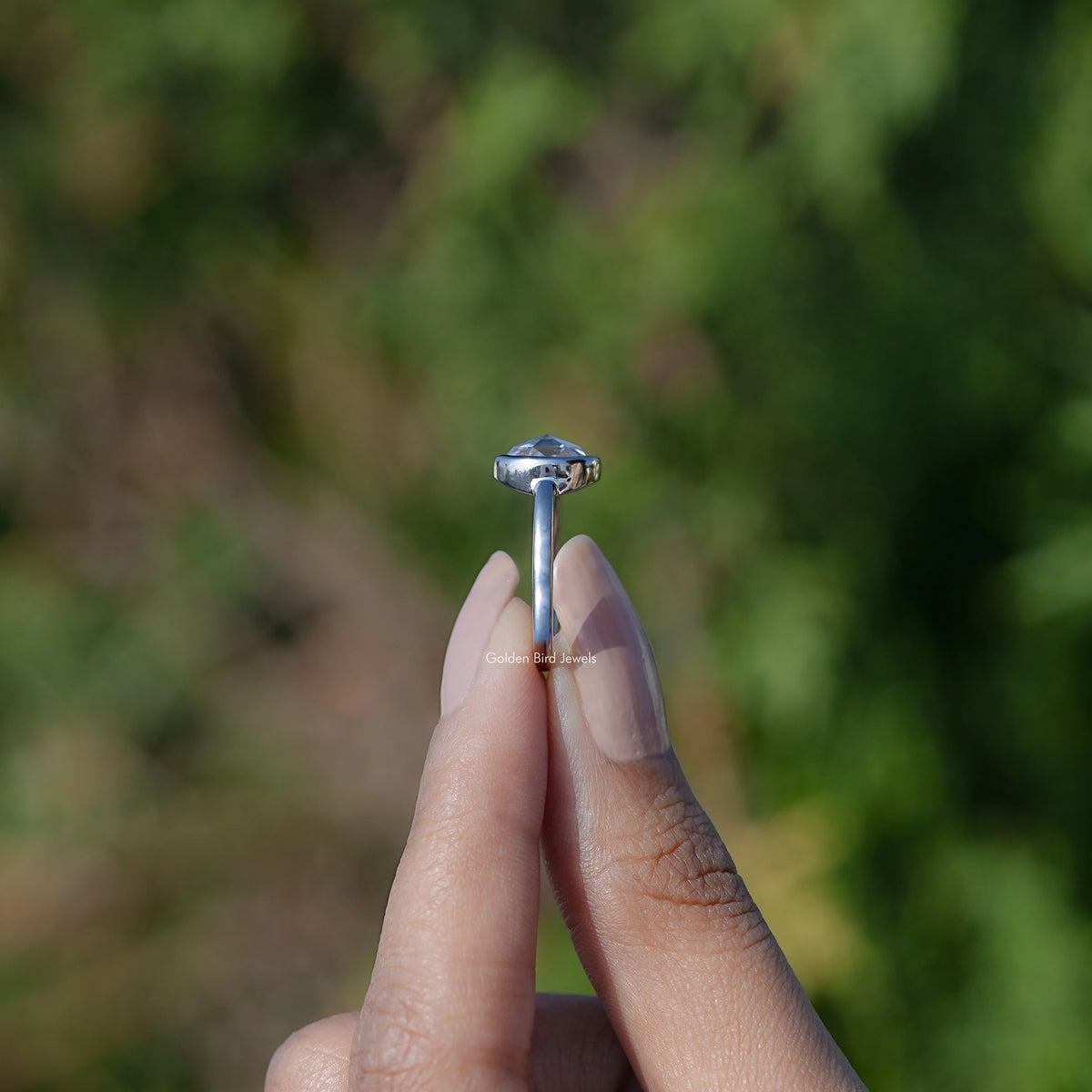 Moissanite solitaire ring side view, prongs holding a round center stone