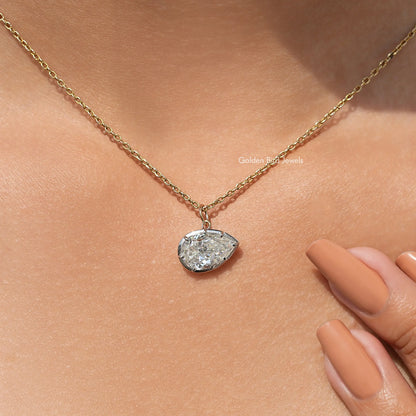 Gold-tone pear-shaped pendant on fine chain, shown near fingers