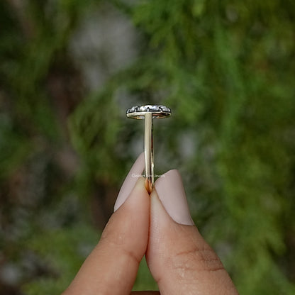 Oval moissanite solitaire ring shown from the side with slender gold-tone band