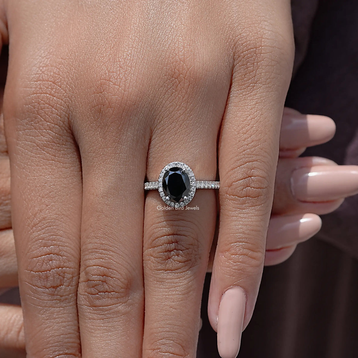 Oval black moissanite halo wedding ring on a hand