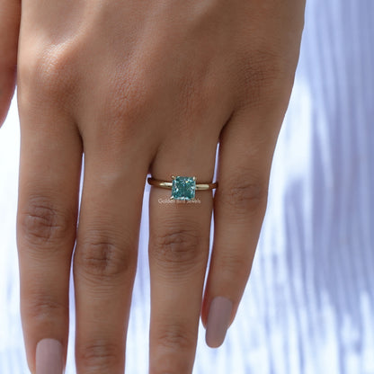 Silver princess-cut solitaire ring with cyan-blue square center stone, full hand view