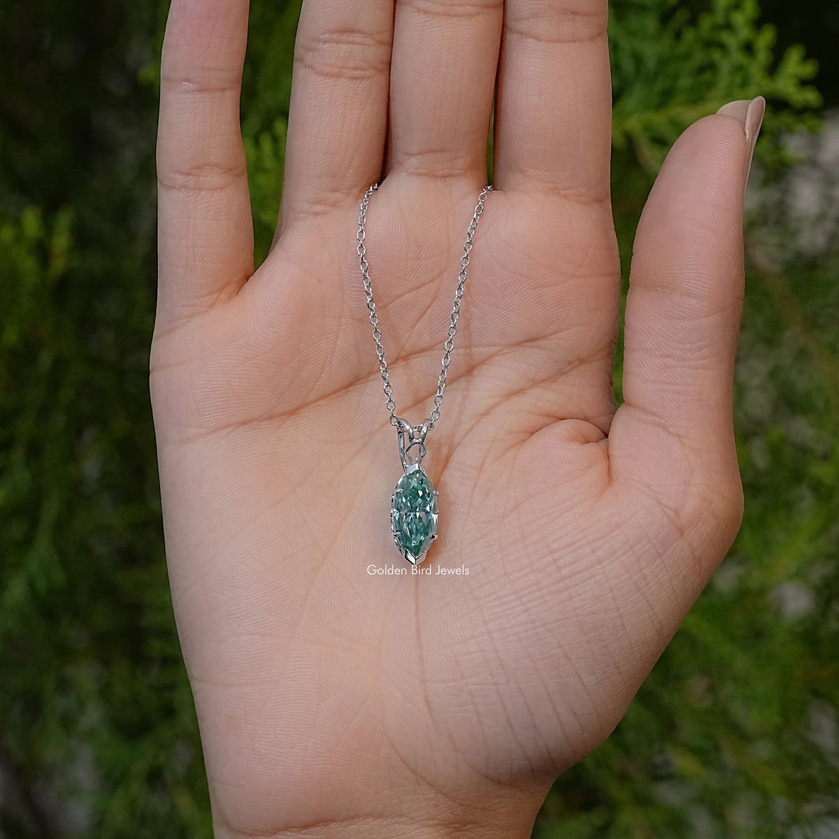 Silver chain marquise-cut green solitaire pendant necklace in palm view with two rings