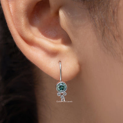 Silver round blue moissanite dangle earring close-up on ear with halo accents