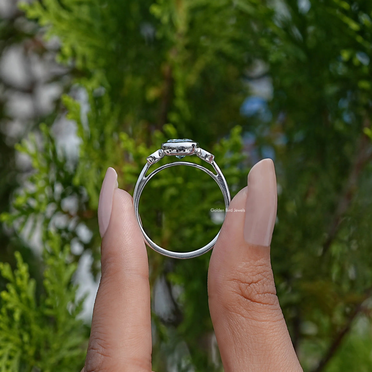 Back view of three-stone cushion-cut moissanite engagement ring on fingers
