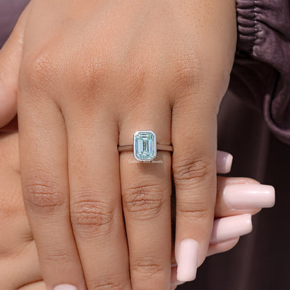 Silver bezel-set blue moissanite solitaire ring on finger with manicured nails