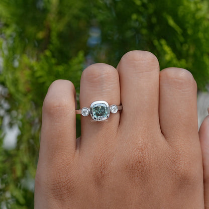 Three-stone cushion-cut moissanite ring on hand, silver band