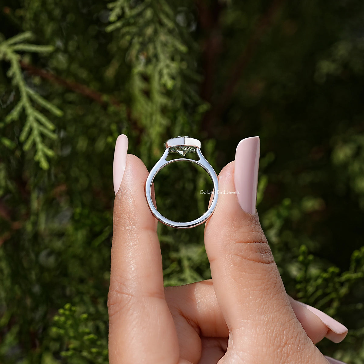 Heart-shaped moissanite bezel ring, sterling silver band shown from front, hands holding