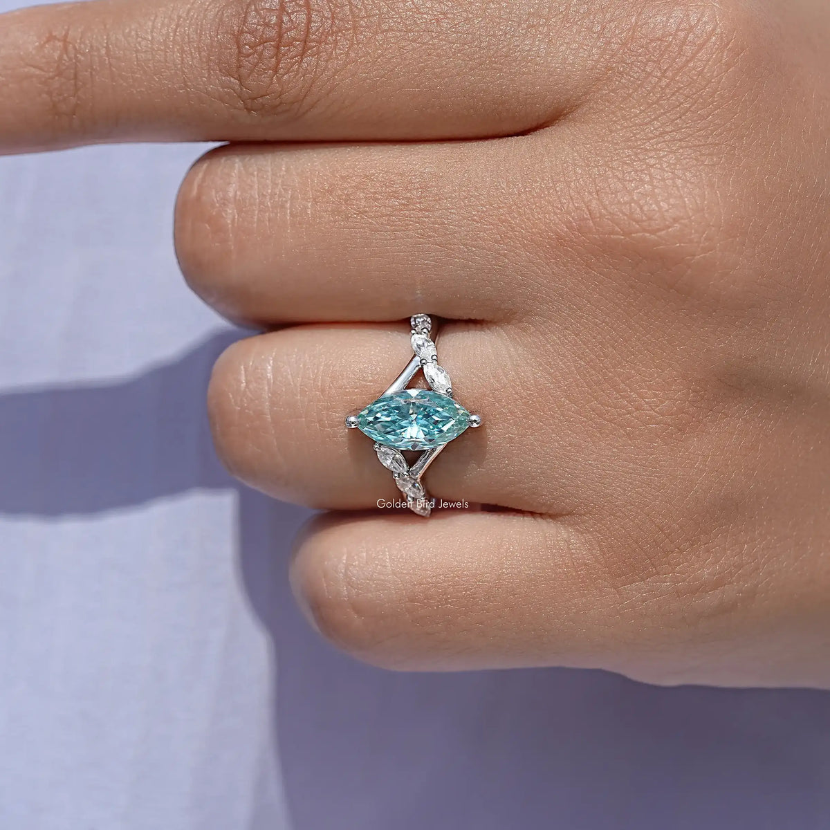 Teal marquise gemstone floral wedding ring close-up on fingertip