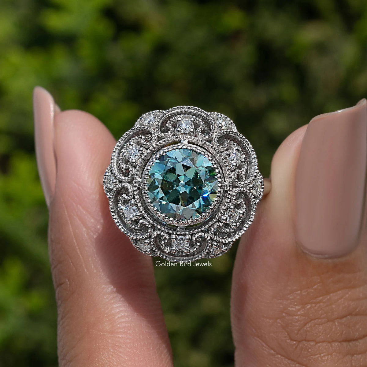 Vintage sterling silver ring with round-cut blue moissanite center and detailed filigree