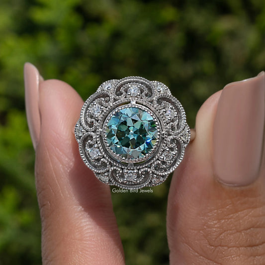 Vintage sterling silver ring with round-cut blue moissanite center and detailed filigree