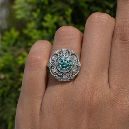 Close-up of vintage round-cut blue moissanite halo in ornate sterling silver
