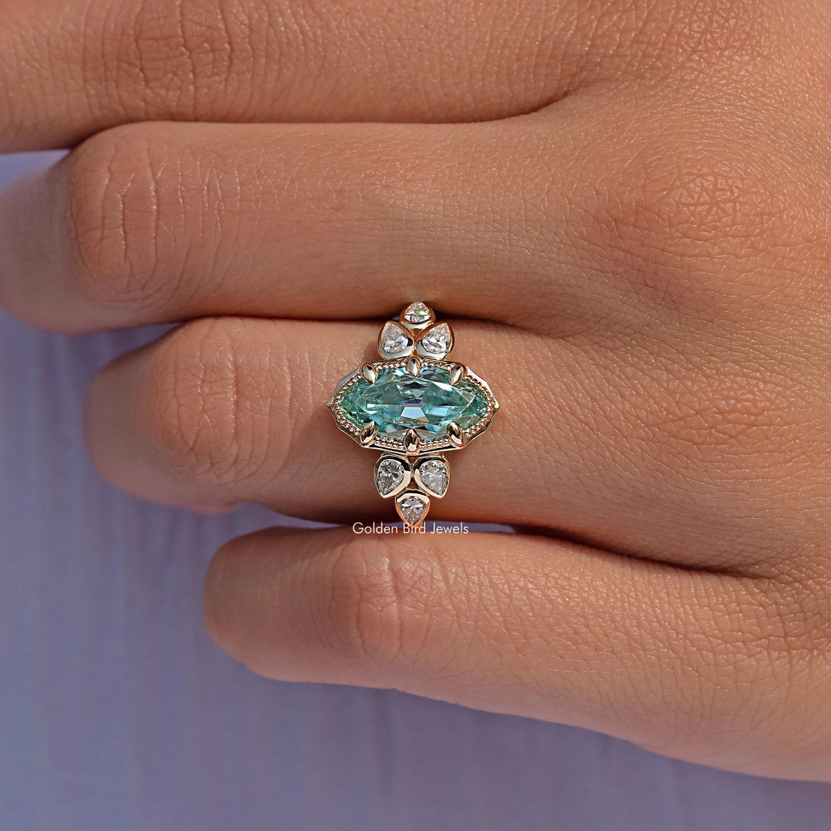Blue oval moissanite ring with small round stones, angled view on fingers