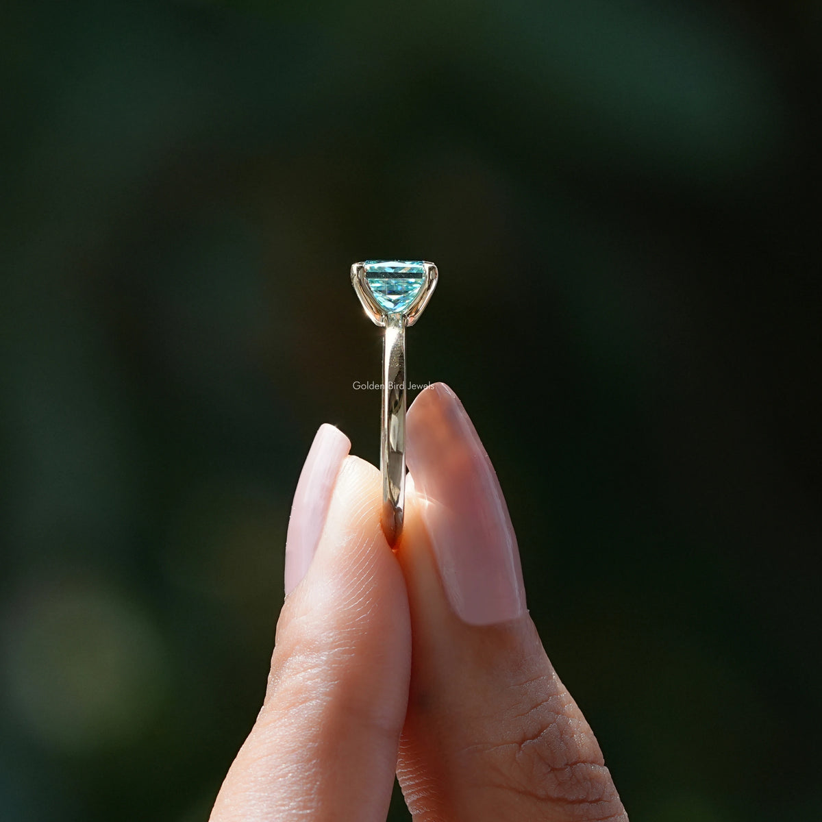 Silver princess-cut solitaire ring side view with cyan-blue square center stone