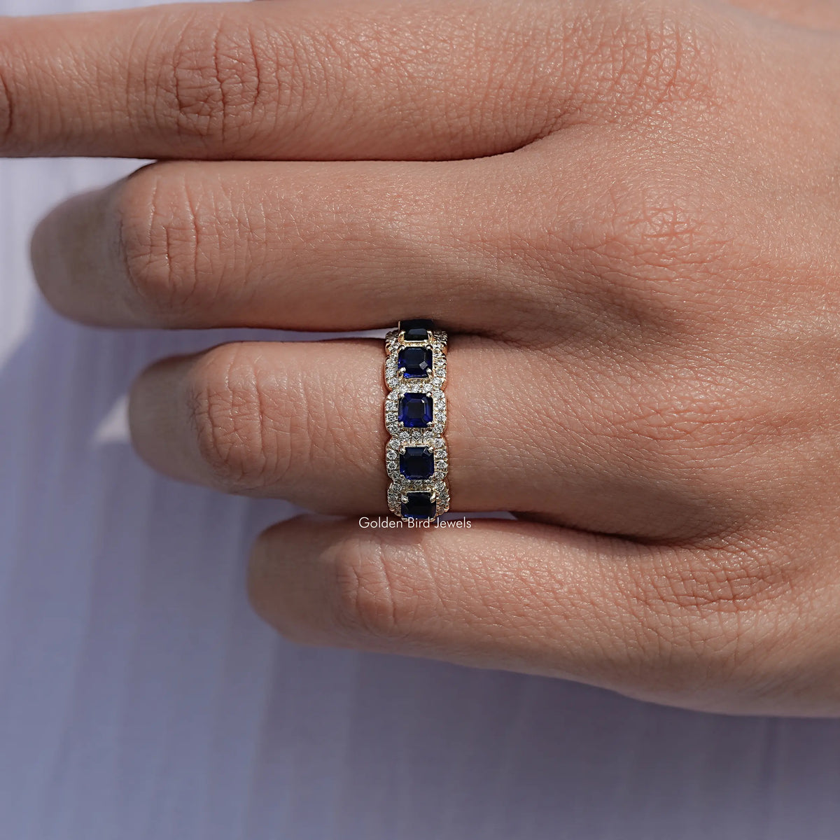 Blue Asscher gemstone halo five-stone band ring on a hand