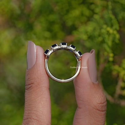 Blue gemstone halo band ring from the side, prong setting visible