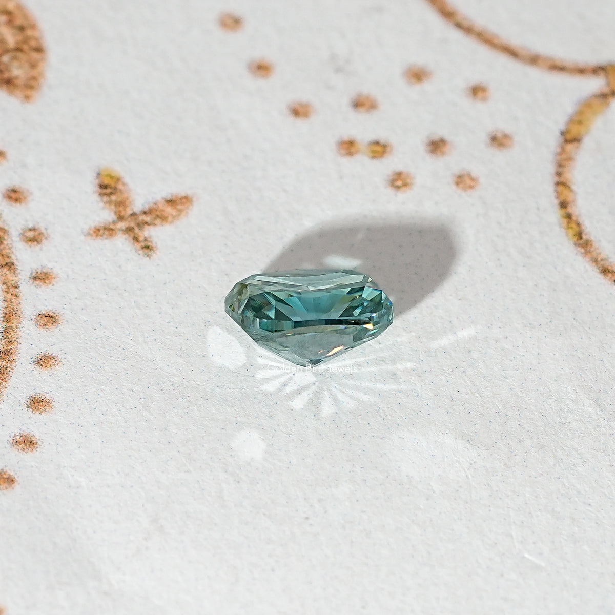 Elongated teal-green moissanite stone, side profile showing facet edges.