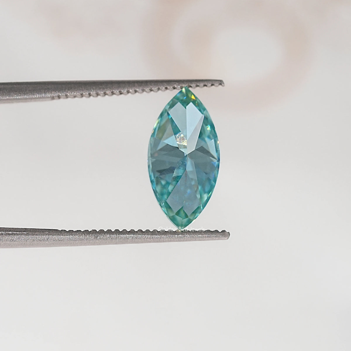 Blue-green marquise-cut moissanite gemstone in tweezers, side profile