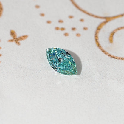 Blue-green marquise-cut loose moissanite gemstone on light gray surface