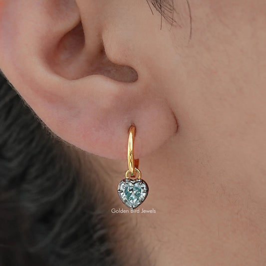 Gold-tone hoop earrings with blue faceted gemstone dangle, close-up