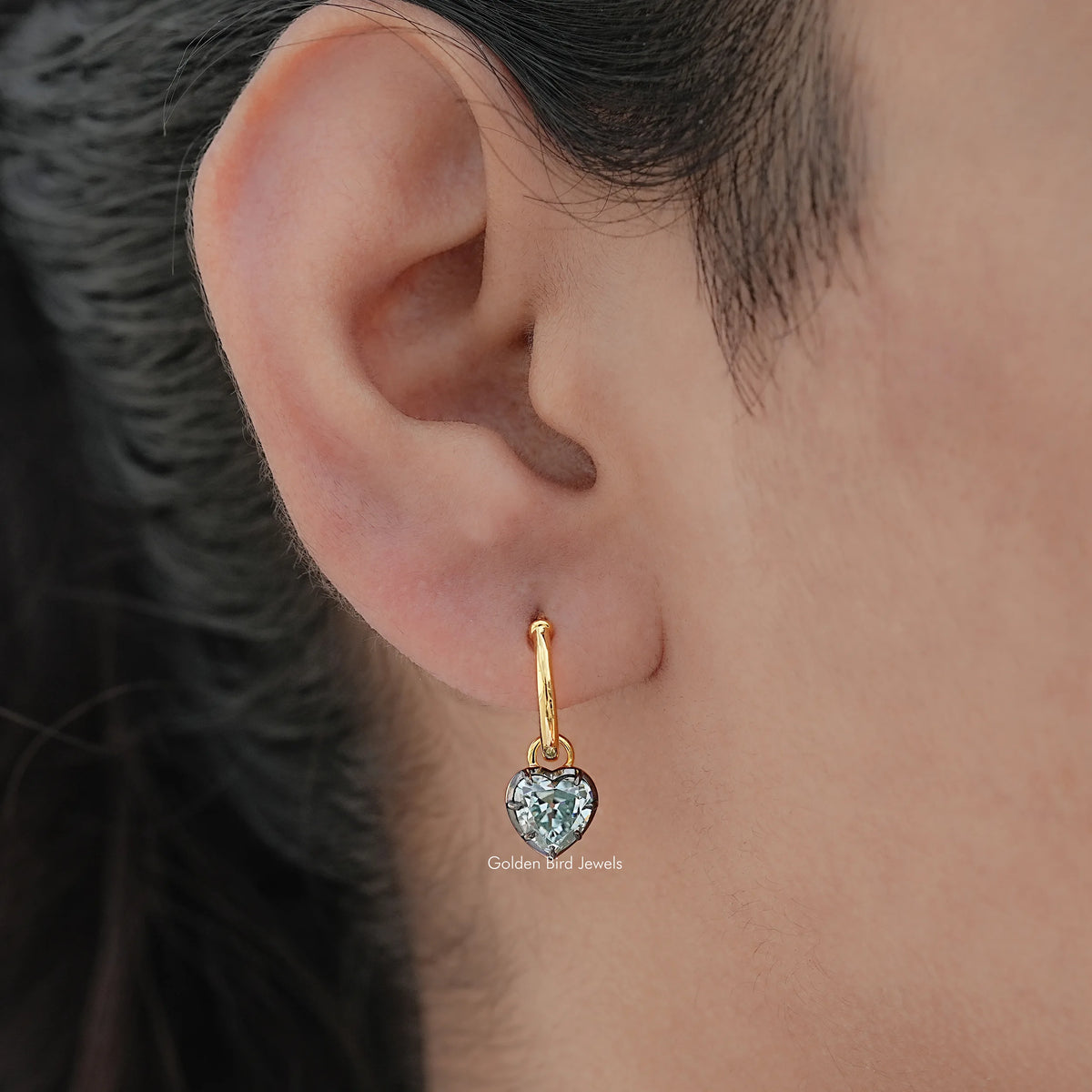 Gold-tone dangle earrings with blue faceted gemstone, side view