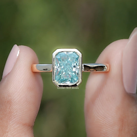 Blue moissanite bezel solitaire ring close-up with rose-gold band rails