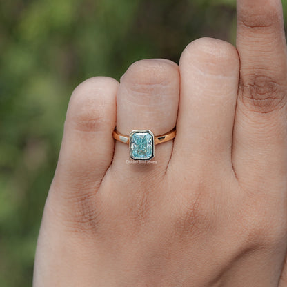 Blue moissanite bezel solitaire ring on finger with slim rose-gold band