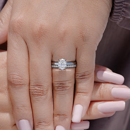Oval-cut moissanite bridal ring set with halo and pavé band on a finger