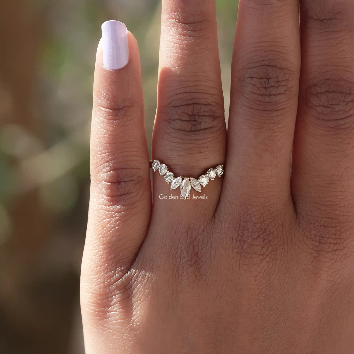 Curved marquise-cut moissanite stacking ring on finger, low-profile gold band