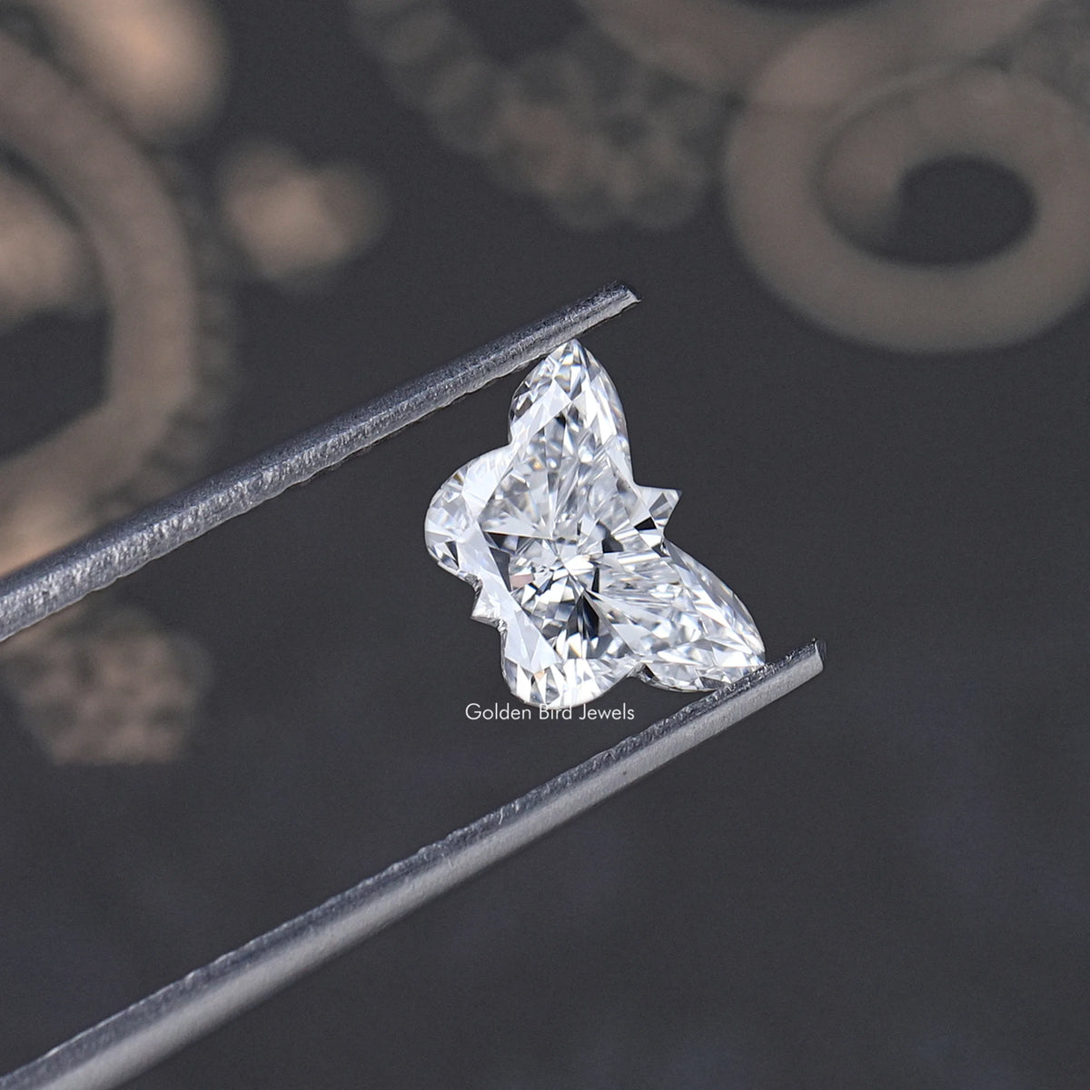 Butterfly-cut lab-grown diamond held on tweezers, detailed sparkle facets