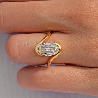 Gold-tone oval stone solitaire ring close-up, bypass band detail on finger